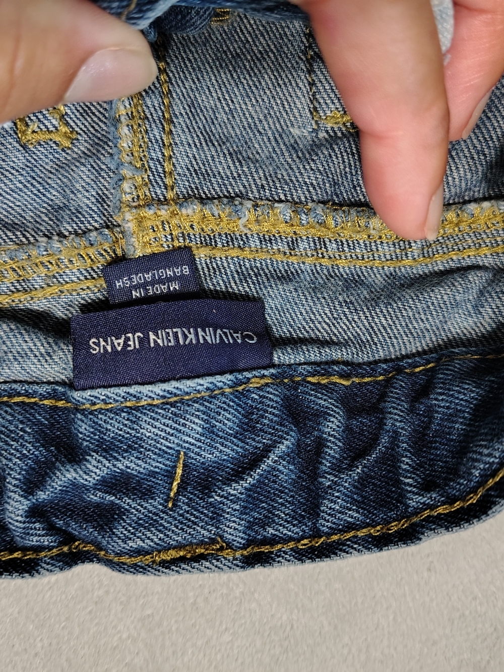 Calvin Klein Jeans navy label on blue denim with yellow stitching